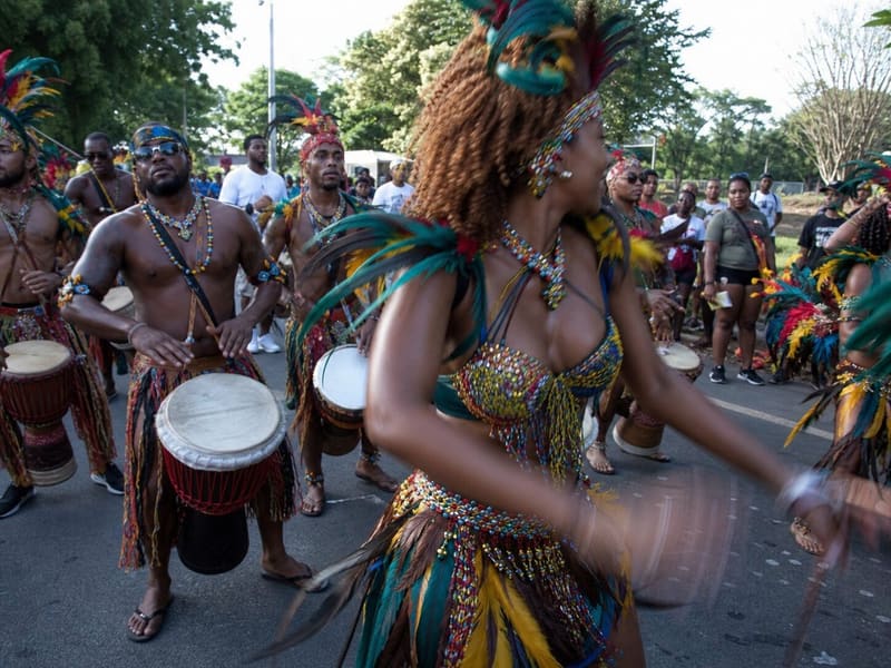 Carnival in Guadeloupe at street level: feathered costume and drums caught mid-movement.