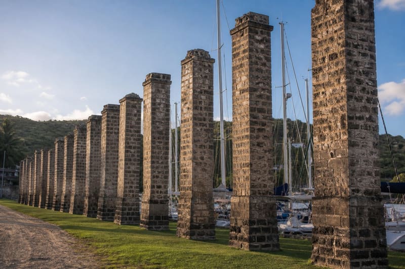 The Georgian pillars of the old sail loft at Nelson’s Dockyard with yacht masts directly behind them.