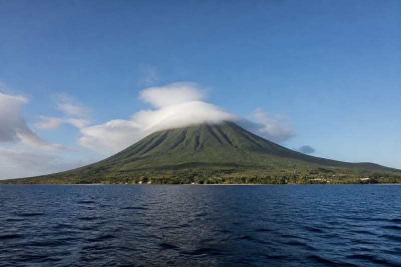 Nevis Peak from the sea: a symmetrical green cone with cloud on the summit.