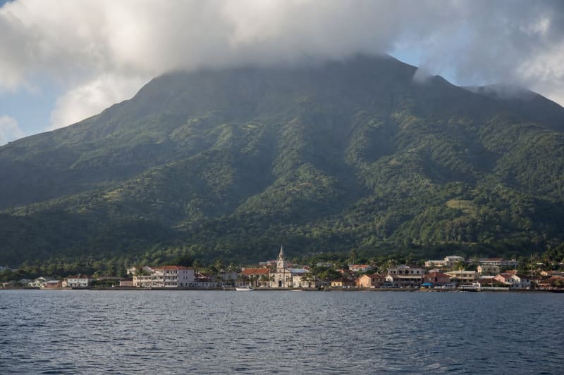 Saint-Pierre, Martinique, from the water with Mont Pelée rising behind the town in cloud.