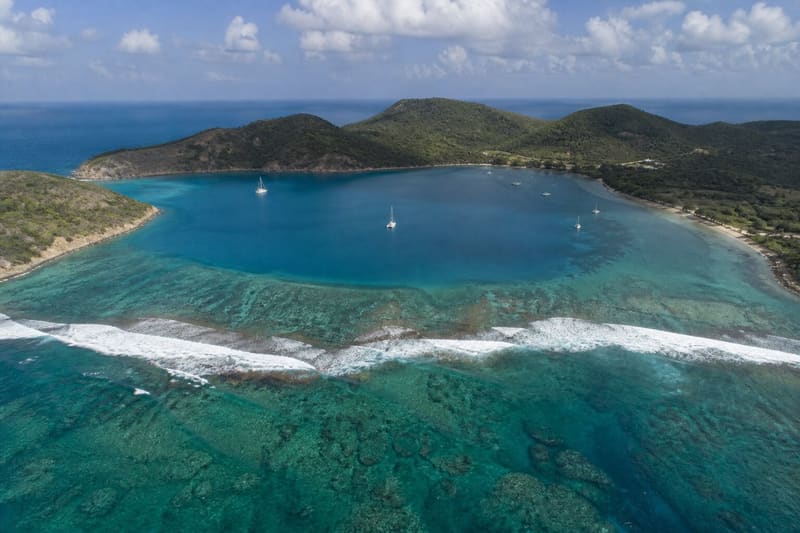 Nonsuch Bay, Antigua, from above: turquoise water inside a white reef line across the mouth of the bay.