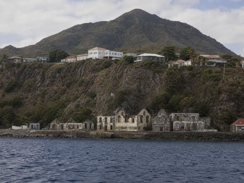Oranjestad, Sint Eustatius, from the water: lower-town ruins at the foot of the cliff, the Quill behind.