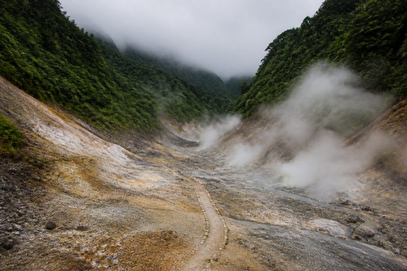 The Valley of Desolation on Dominica: a barren grey and ochre volcanic valley venting steam, rainforest walls rising steeply on both sides.